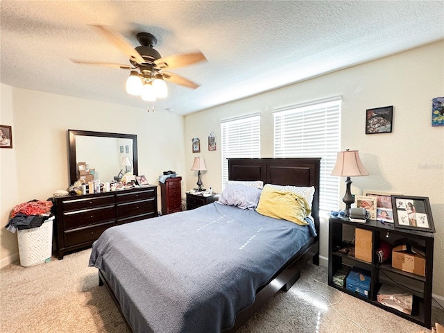 bedroom featuring a textured ceiling, baseboards, a ceiling fan, and light colored carpet