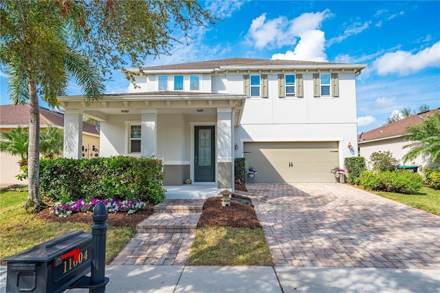 view of front facade featuring a porch, decorative driveway, an attached garage, and stucco siding