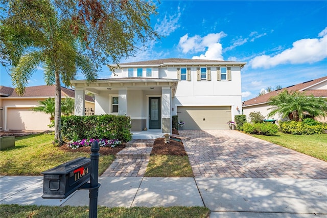 view of front facade with stucco siding, an attached garage, covered porch, decorative driveway, and a front yard