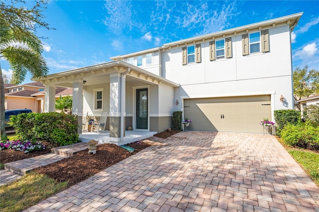 view of front of property with an attached garage, covered porch, decorative driveway, and stucco siding