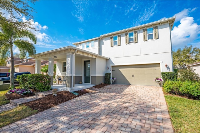 view of front of house with a porch, decorative driveway, a garage, and stucco siding