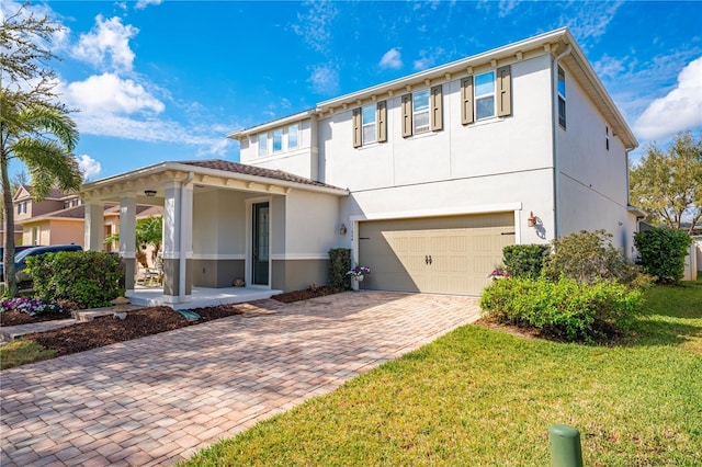 view of front of property with a garage, a front lawn, decorative driveway, and stucco siding