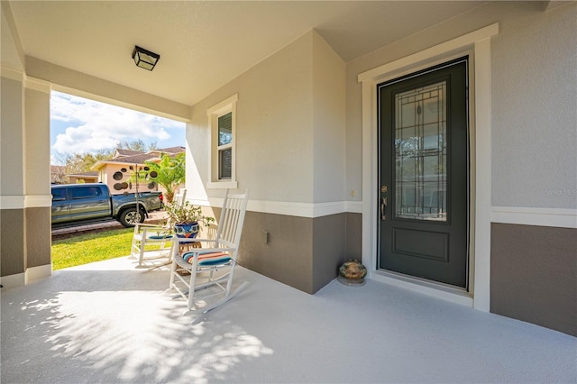 doorway to property with covered porch and stucco siding