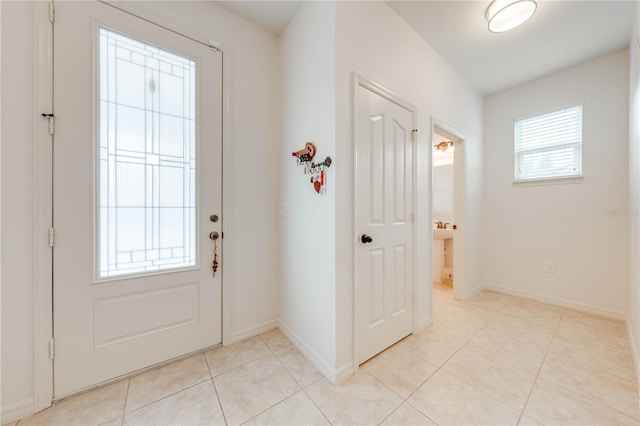 doorway to outside with light tile patterned flooring and baseboards