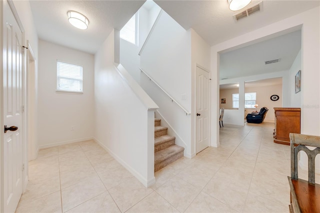 stairway featuring tile patterned flooring, visible vents, and baseboards