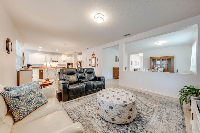 living area with a textured ceiling, visible vents, and recessed lighting