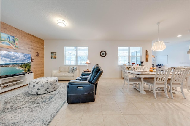 living area with wood walls, a textured ceiling, a wealth of natural light, and light tile patterned flooring