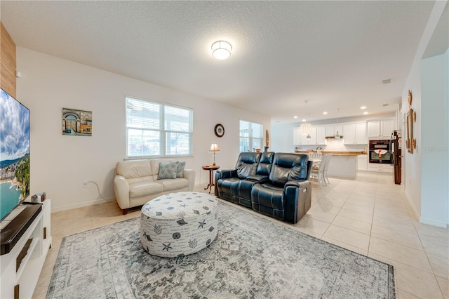 living room with baseboards, visible vents, light tile patterned flooring, a textured ceiling, and recessed lighting