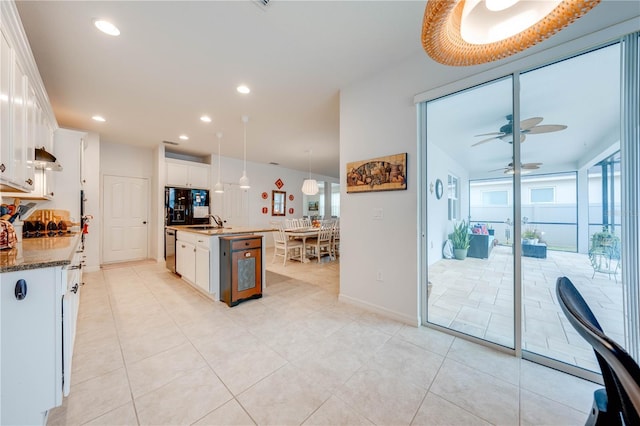 kitchen with a healthy amount of sunlight, a kitchen island with sink, white cabinets, and a sink