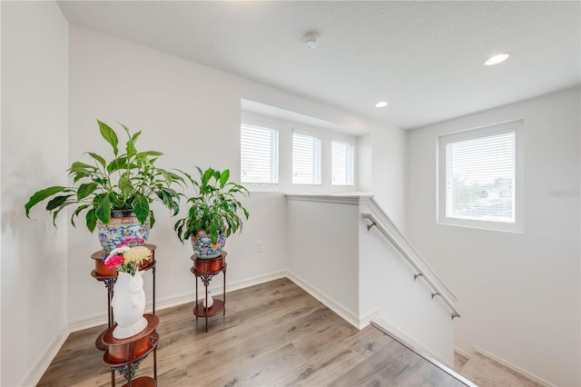 living area featuring recessed lighting, baseboards, light wood-style flooring, and an upstairs landing