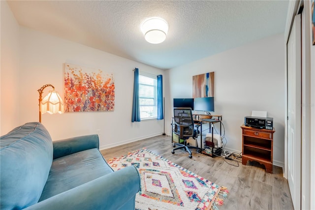 office with a textured ceiling, baseboards, and wood finished floors