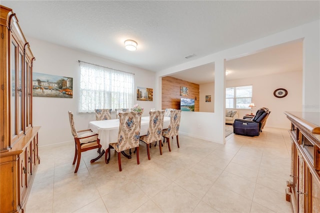 dining area featuring light tile patterned floors, baseboards, and a textured ceiling