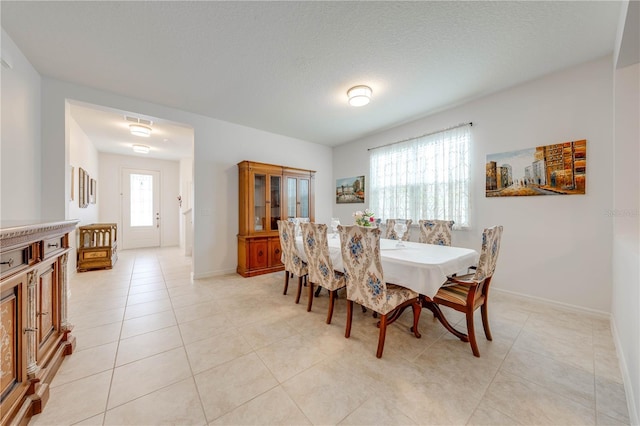 dining space with light tile patterned floors, visible vents, baseboards, and a textured ceiling