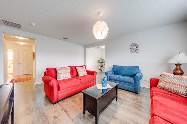 living area featuring visible vents, a textured ceiling, and light wood finished floors