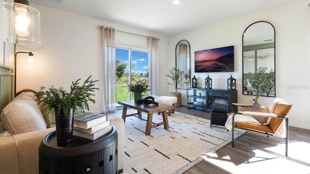 interior space featuring light wood-style flooring, baseboards, and a glass covered fireplace