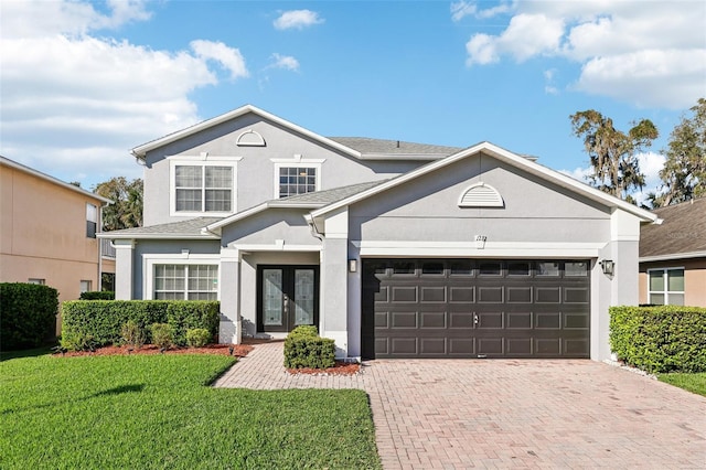 traditional home with decorative driveway, an attached garage, a front lawn, and stucco siding