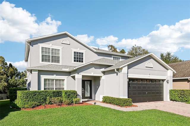 traditional home featuring a garage, stucco siding, decorative driveway, and a front yard