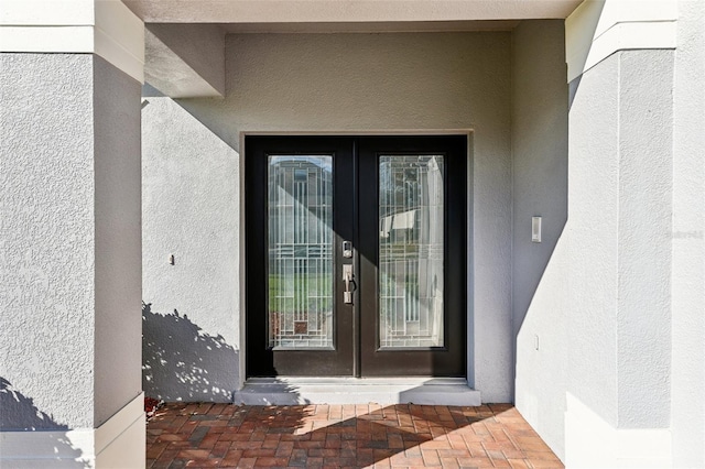 entrance to property featuring french doors and stucco siding