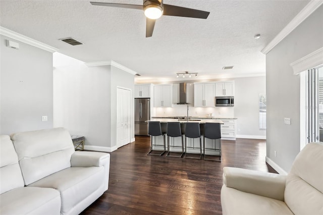 living area featuring a textured ceiling, visible vents, dark wood finished floors, and crown molding