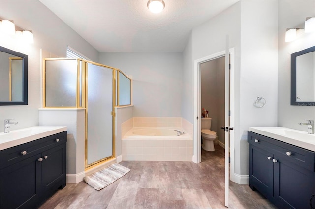 bathroom with wood finished floors, a sink, toilet, and a shower stall