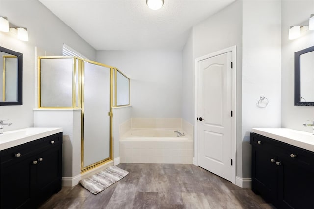 full bathroom featuring a garden tub, two vanities, a sink, a shower stall, and wood finished floors