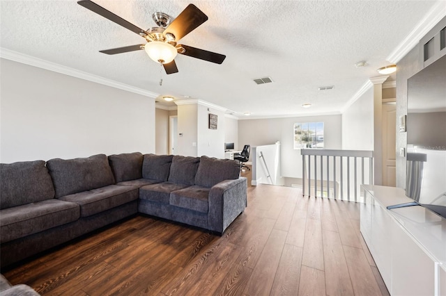 living area featuring a textured ceiling, dark wood-style flooring, visible vents, and crown molding