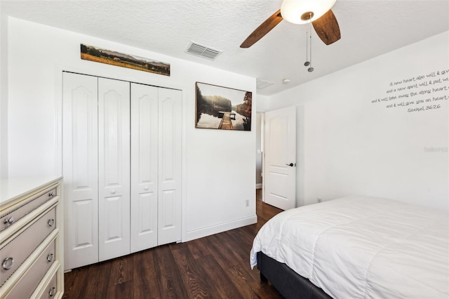 bedroom featuring ceiling fan, a textured ceiling, visible vents, a closet, and dark wood-style floors