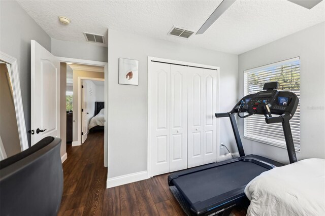 workout area with dark wood-style floors, baseboards, visible vents, and a textured ceiling