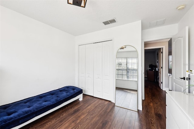 bedroom with a closet, dark wood-style flooring, visible vents, and baseboards