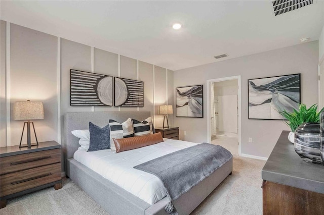 bedroom with light colored carpet, visible vents, baseboards, and ensuite bathroom