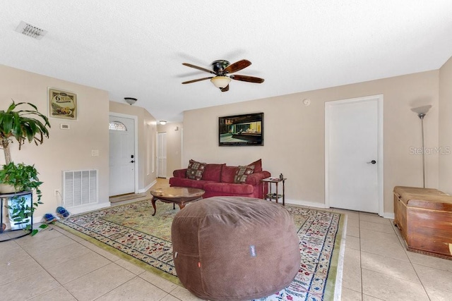 living area with light tile patterned floors, ceiling fan, visible vents, and a textured ceiling