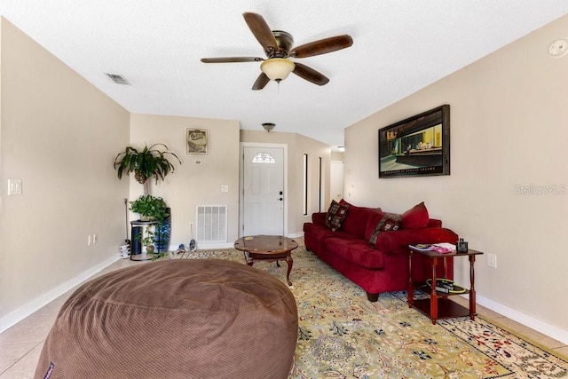 living area with ceiling fan, light tile patterned floors, visible vents, and baseboards