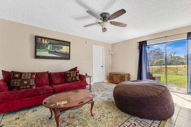 living room featuring a ceiling fan, a textured ceiling, and light tile patterned floors