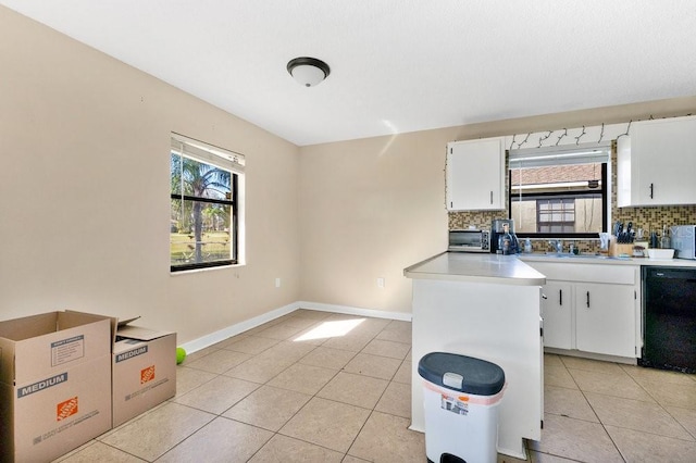 kitchen with white cabinets, black dishwasher, light countertops, and backsplash