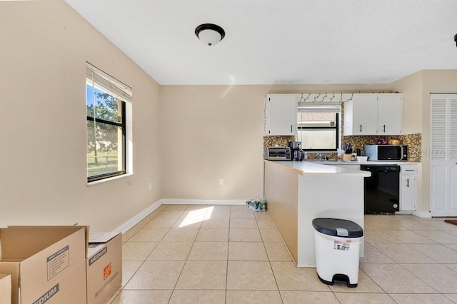 kitchen with black dishwasher, light countertops, light tile patterned flooring, and white cabinets