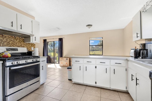 kitchen with light countertops, decorative backsplash, stainless steel range with gas stovetop, white cabinetry, and under cabinet range hood