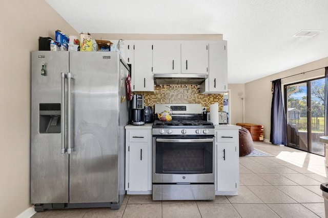 kitchen with light tile patterned flooring, under cabinet range hood, white cabinetry, appliances with stainless steel finishes, and tasteful backsplash