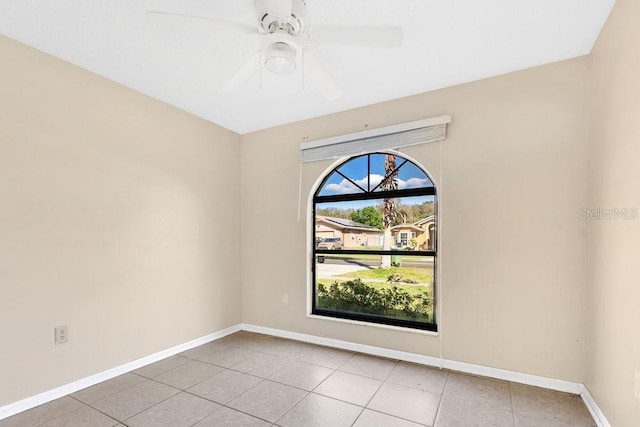 empty room with tile patterned flooring, ceiling fan, and baseboards