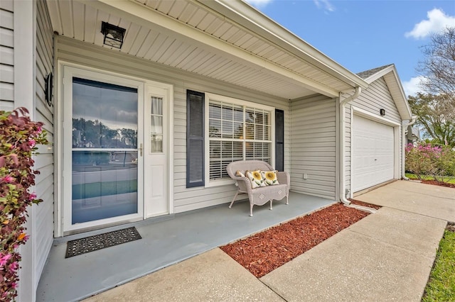 property entrance with an attached garage, covered porch, and concrete driveway