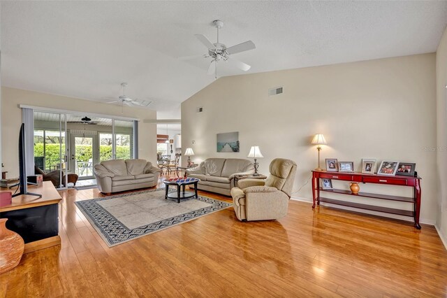 living area with visible vents, hardwood / wood-style floors, a ceiling fan, vaulted ceiling, and baseboards