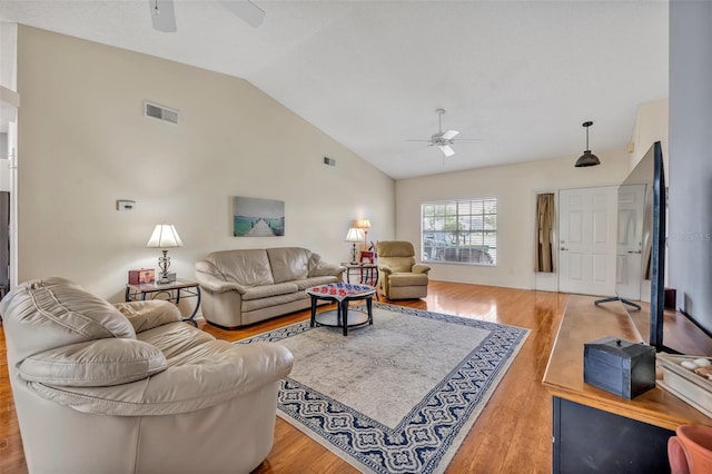 living room with a ceiling fan, visible vents, vaulted ceiling, and wood finished floors