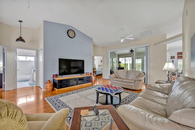 living room with lofted ceiling, visible vents, light wood-style flooring, and a ceiling fan