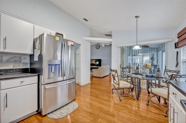 kitchen featuring light wood-style floors, white cabinets, stainless steel fridge with ice dispenser, dark countertops, and decorative light fixtures