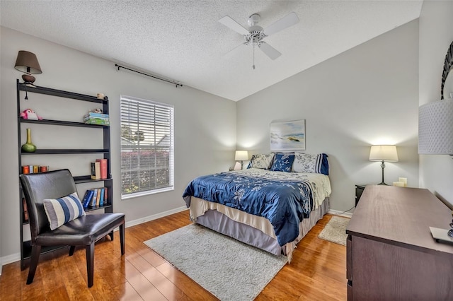 bedroom featuring a textured ceiling, baseboards, vaulted ceiling, and wood finished floors