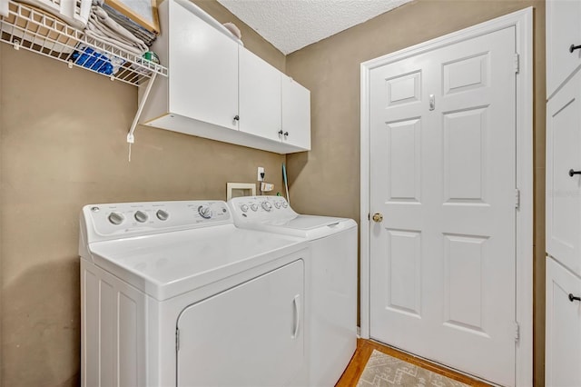 laundry area with a textured ceiling, separate washer and dryer, and cabinet space