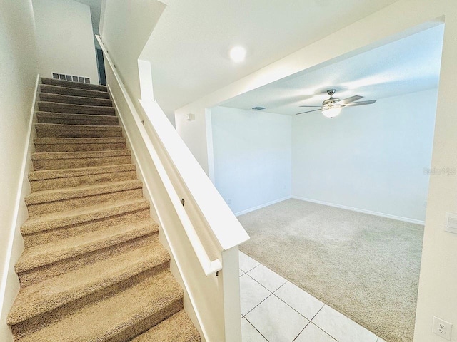 stairs with baseboards, carpet, a ceiling fan, and tile patterned floors