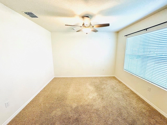 unfurnished room with light colored carpet, visible vents, a ceiling fan, a textured ceiling, and baseboards