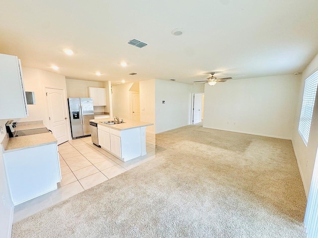 kitchen featuring light carpet, a kitchen island with sink, white cabinets, and stainless steel appliances