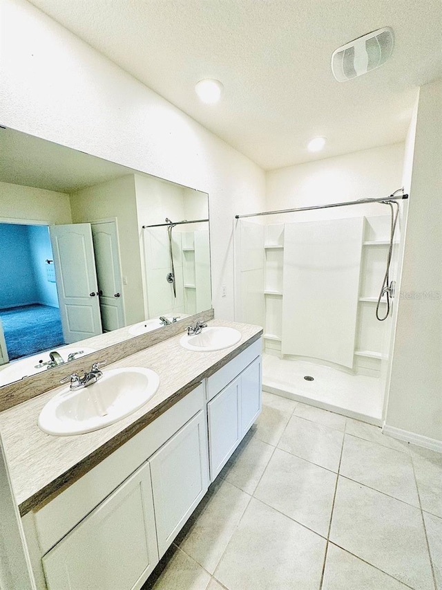 ensuite bathroom featuring visible vents, a sink, a shower stall, and tile patterned floors