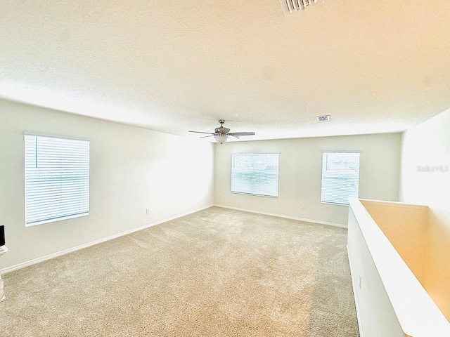 spare room featuring light carpet, a textured ceiling, and visible vents